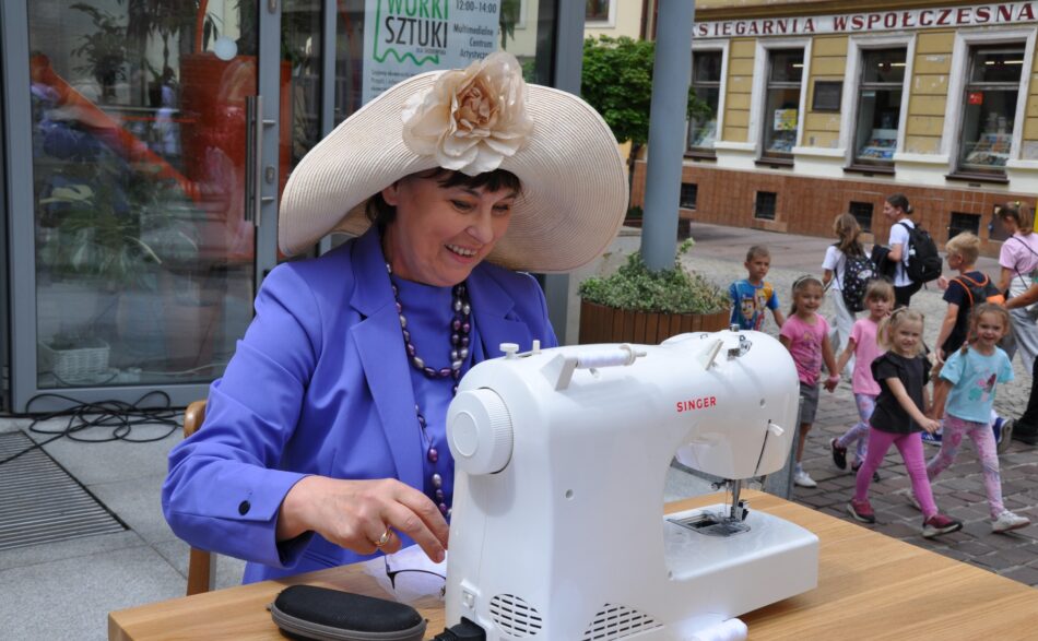 Kobieta w kapeluszu szyje na maszynie woreczek z firanki