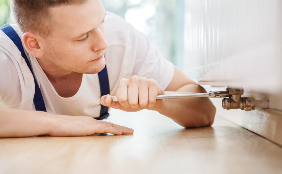 Osoba naprawiająca kaloryfer