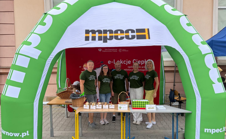 Pięcioro pracowników MPEC Tarnów w zielonych koszulkach z napisem "Dbamy o dobry klimat dla Tarnowa" na stoisku promocyjnym MPEC Tarnów zorganizowanym podczas pikniku Biblioteczna Odyseja.